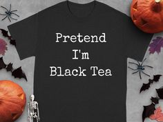 Discover our funny Halloween T-shirt with "Pretend I'm Black Tea" design. Perfect for parties, this tee offers a humorous twist for any tea lover. Enjoy comfort and style while showcasing your playful side. Ideal for mixing and matching with your favorite outfits for every occasion! Product Features: Fabrication: Medium fabric (5.3 oz/yd² (180 g/m 100% cotton (fiber content may vary for different colors) Seams: Without side seams Fit: Classic Fit Sizing: Family Sizing Label: Tear-away label Halloween Black T-shirt With Text Print, Halloween Funny Print Orange T-shirt, Spooky Black T-shirt With Funny Print, Funny Cotton Halloween T-shirt, Funny Halloween T-shirt With Short Sleeves, Tea Design, Tea Lovers Gift, Black Tea, Fete Halloween