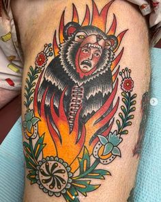 a man's thigh with a bear and flames tattoo on the side of his leg