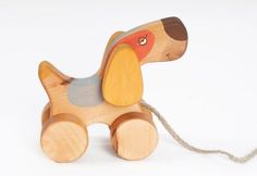 a wooden toy dog sitting on top of a white floor next to a string attached to it