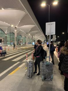 people waiting at an airport with luggage on the ground and in line for their bags to be picked up