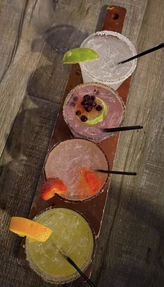 four different types of drinks sitting on top of a wooden table