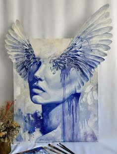 a painting with wings on top of it next to some paintbrushes and brushes