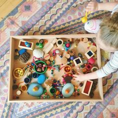 a young child playing with toys in a wooden box on the floor at home or playroom