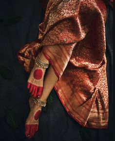 a woman's feet with red and gold accessories on her hands, in an image taken from above