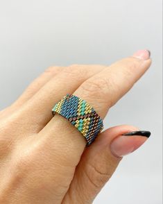 a woman's hand with a ring on her finger, wearing a multicolored beaded band