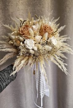 a bouquet of flowers is being held up by someone's hand in front of a curtain