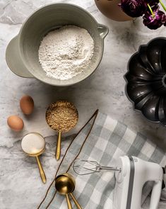 an overhead view of kitchen utensils and ingredients on a marble counter top with flowers in the background