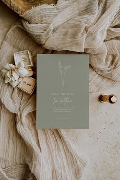 a wedding suite and ring on top of a bed with a white flower next to it