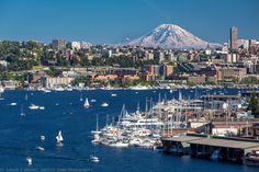 boats are in the water near a city with a mountain in the backgroud