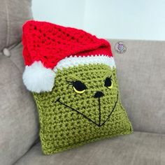 a green crocheted christmas stocking with a red santa hat on it's head