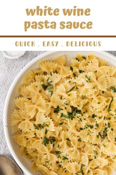 a white bowl filled with pasta and parsley on top of a striped table cloth