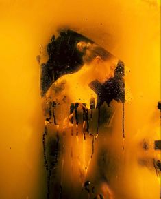 a woman's reflection is shown through a glass window with yellow and black paint