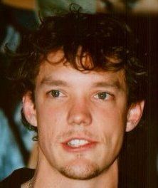 a young man with curly hair is looking at the camera