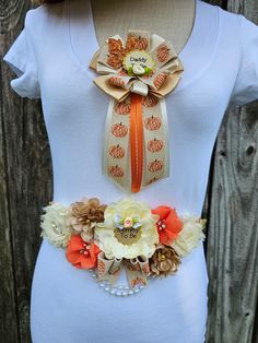 a woman's white shirt with an orange and yellow flower belt attached to it