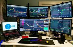 multiple computer monitors and laptops on a desk in front of a wall with graphs