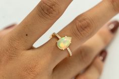 a woman's hand with a ring that has an opal stone on it