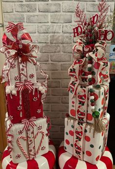 two christmas gifts stacked on top of each other in front of a brick wall with red and white decorations