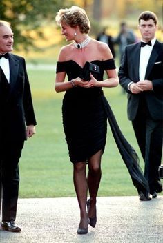 two men in tuxedos and a woman in a black dress walking down the street