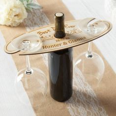 two wine glasses and a bottle sitting on a table with a lace placemat in the middle