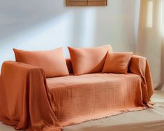 an orange couch is in front of a window