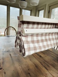 a wooden table topped with a white and brown checkered cloth hanging from the ceiling