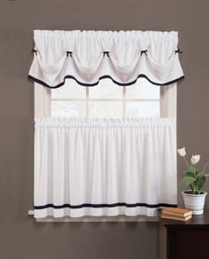 a kitchen window with a white curtain and red trim on the valance, next to a potted plant