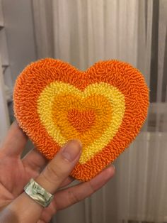 a hand holding an orange and yellow knitted heart