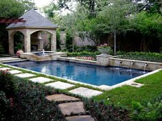 an outdoor pool surrounded by greenery and landscaping