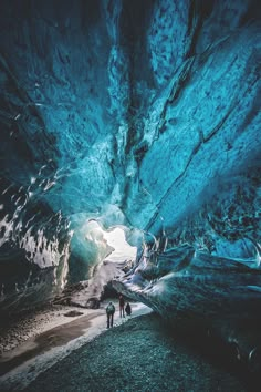 two people are walking through an ice cave