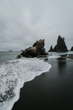 an ocean beach with rocks in the background