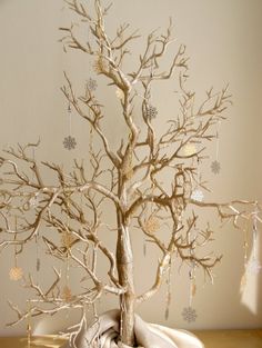 a small tree with ornaments hanging from it's branches in front of a wall