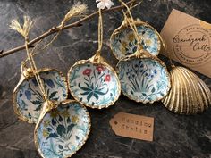 four blue and white dishes hanging from a tree branch with a tag on the side