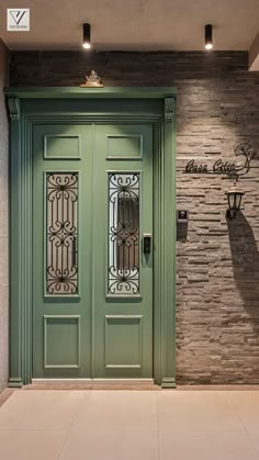 a green door in front of a stone wall with wrought iron grills on it