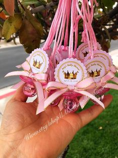 a person holding up some pink ribbons with crowns on them