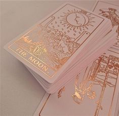 three playing cards with gold foil on them sitting next to each other, one has the moon in it