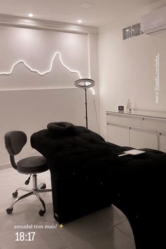 a black couch sitting in front of a white wall next to a chair and lamp