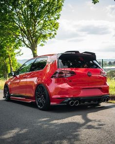 the rear end of a red volkswagen golf gtr parked in front of a tree