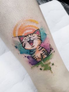 a cat tattoo on the leg with watercolor paint splatters and an orange sun in the background