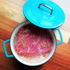 a blue pot filled with meat on top of a wooden table