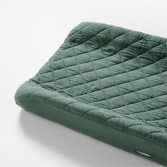 a green mattress sitting on top of a white floor