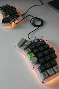 two computer keyboards sitting next to each other on a white table with wires and plugs