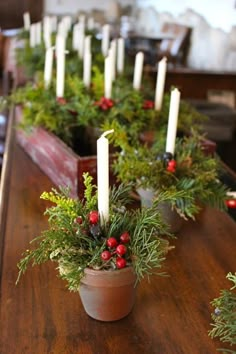 a table with candles and greenery in pots on it's sides, along with other decorations