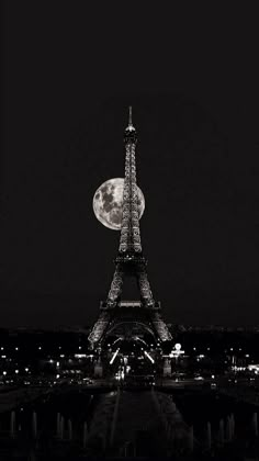 the eiffel tower lit up at night in black and white with full moon