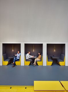 three people sitting on benches in the middle of a room with yellow and gray walls