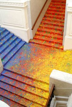 an orange and blue stair case next to a red carpeted staircase with yellow paint on it