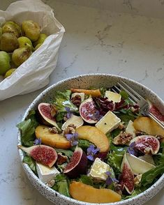 a bowl filled with salad next to a bag of fruit