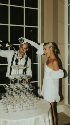 a man and woman standing in front of a table with wine glasses on top of it