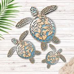 three wooden cutouts of sea turtles on a white wood background with palm leaves and a potted plant