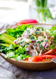 a salad with lettuce, tomatoes and chicken in a bowl on a table