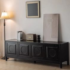 a living room with a black entertainment center next to a lamp and pictures on the wall